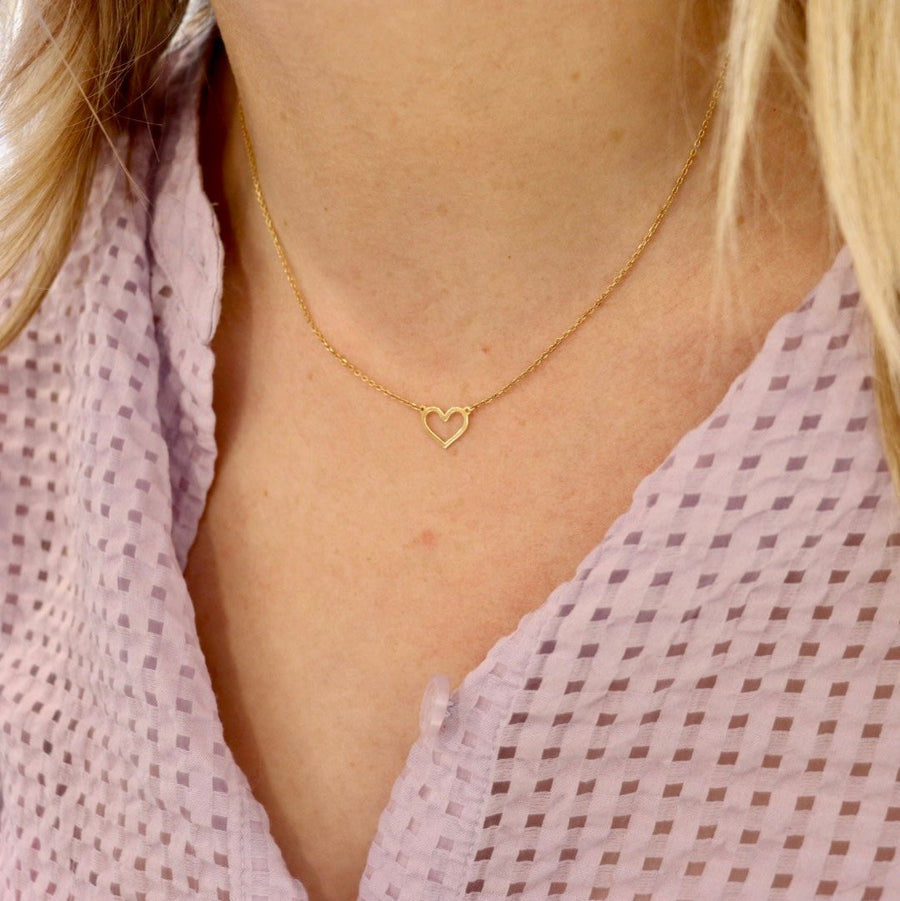 a side shot of a 9ct gold open heart necklace on a woman's neck