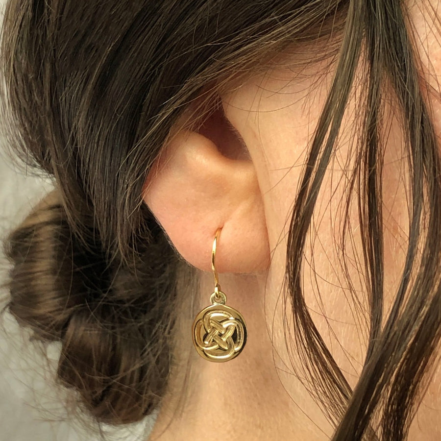 dara knot drop earrings on a woman's ear