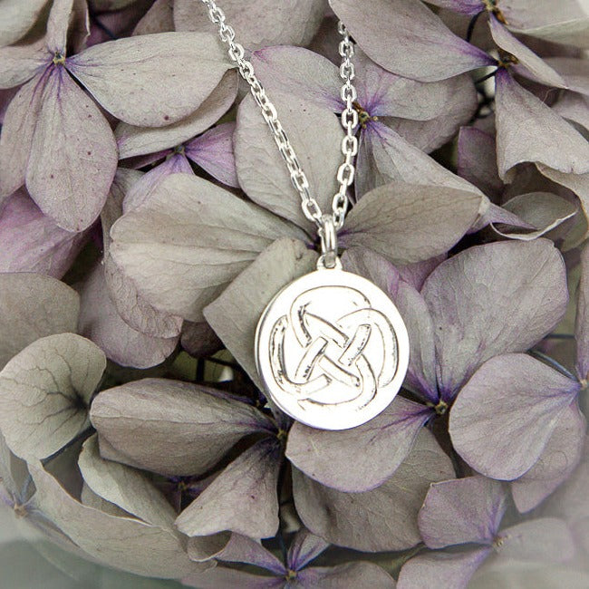 sterling silver necklace symbolic for strength against purple flowers